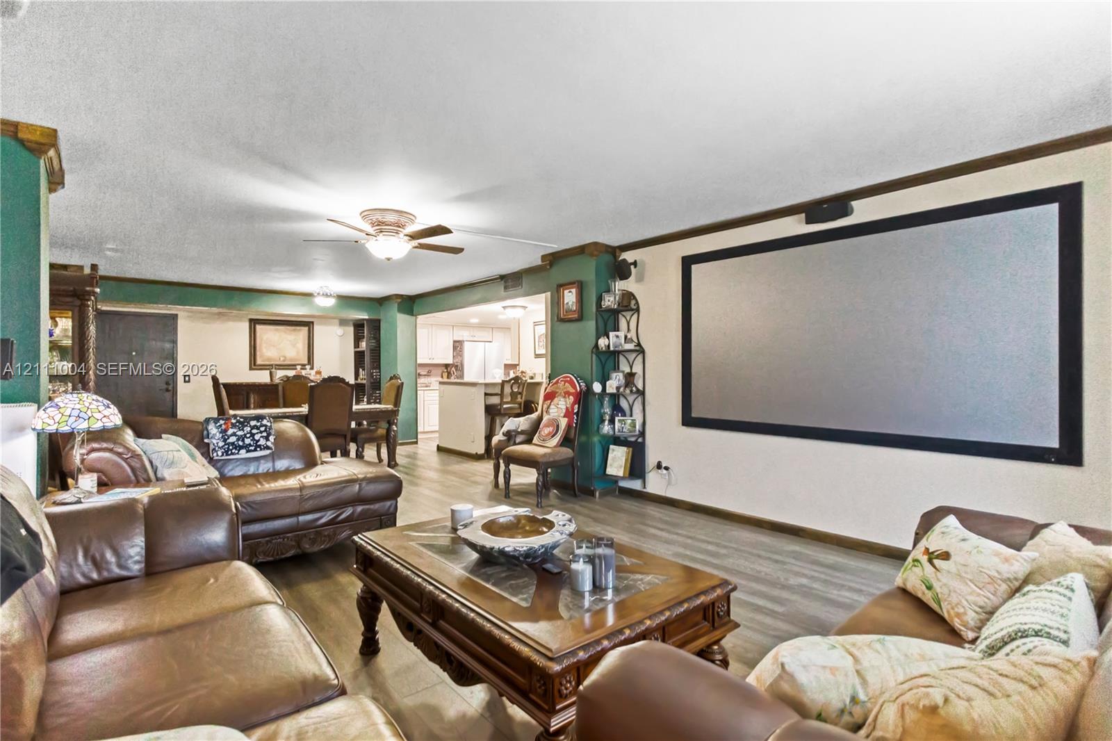 Open-concept area featuring wood-finish flooring, a wall-mounted projection screen, and ceiling fan