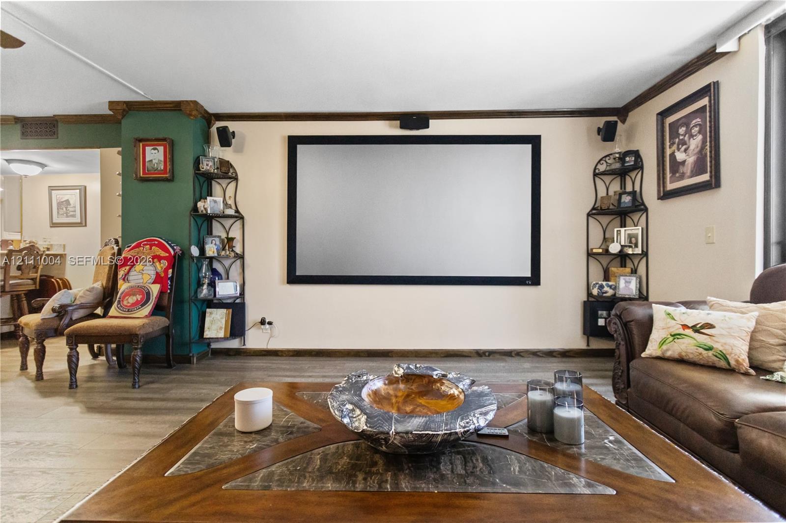 Wall-mounted projector screen, built-in recessed wall shelving, wood-finish flooring, and crown molding