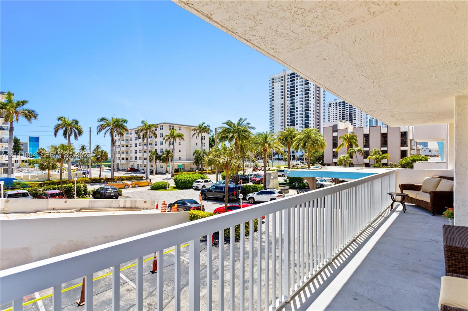Covered balcony featuring concrete flooring and a white metal railing