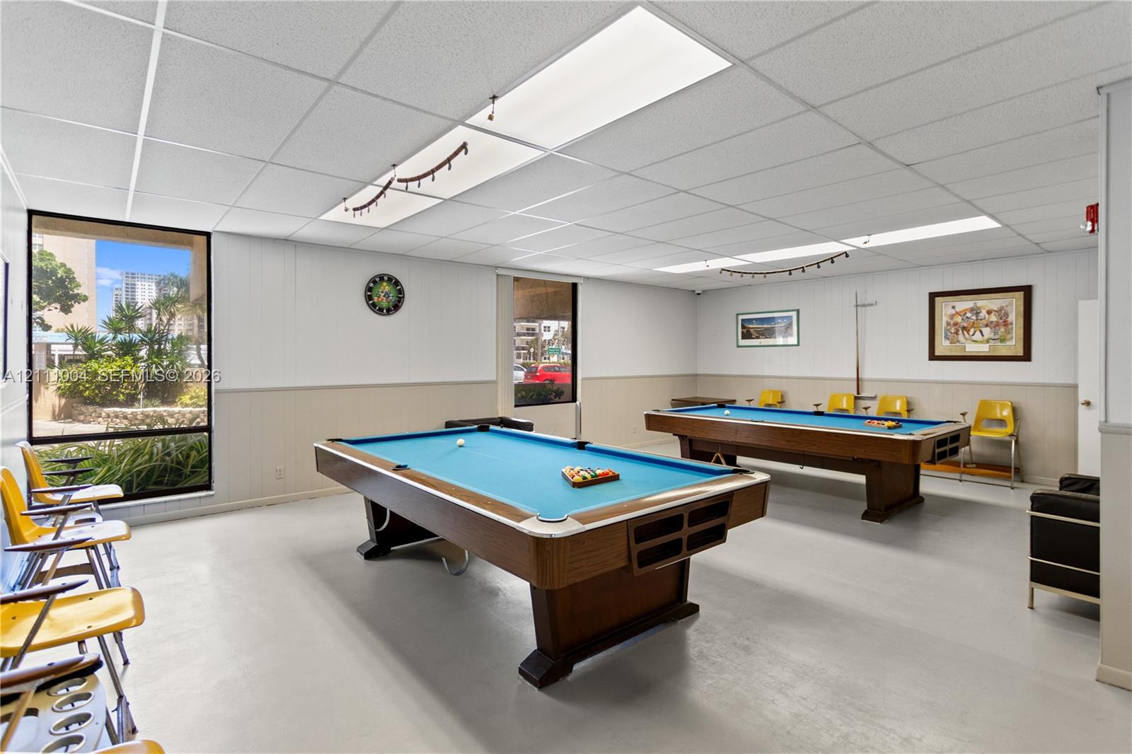 Recreation room featuring recessed drop-ceiling lighting, large picture windows, and dual-toned wall paneling