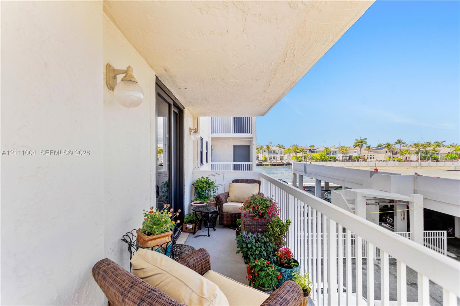 Covered balcony featuring concrete flooring, white metal railing, and wall-mounted exterior globe lighting