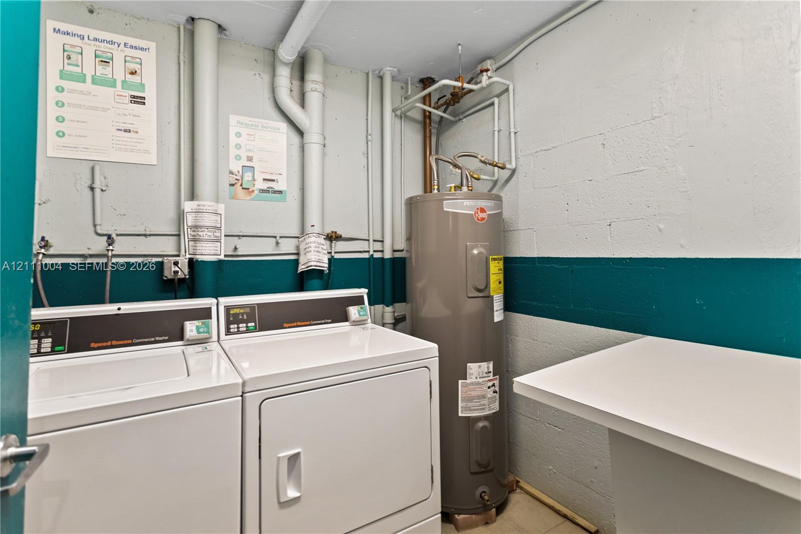 Utility area featuring a water heater, dual laundry appliances, and a built-in counter