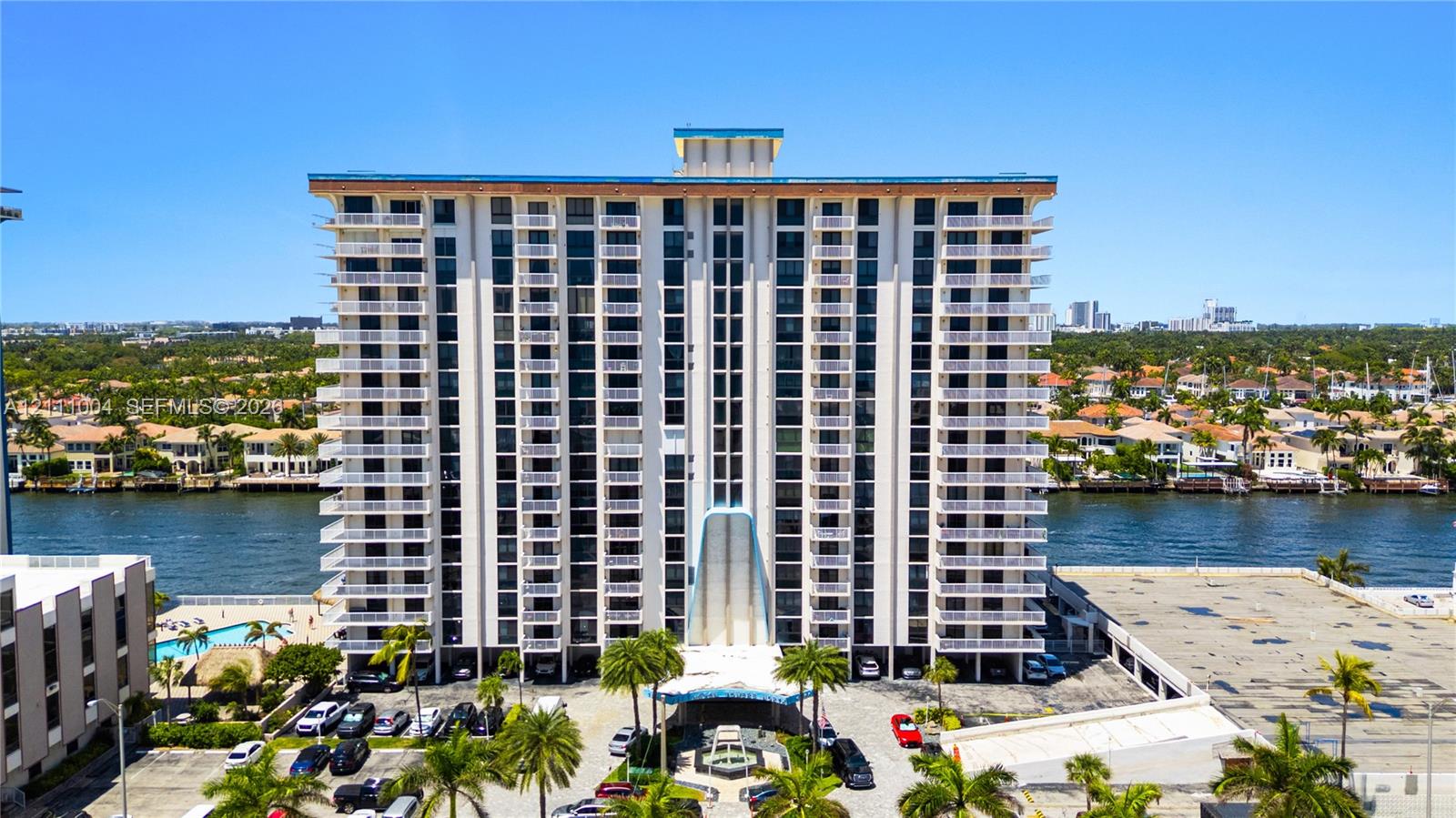 Multi-story residential building featuring symmetrical private balconies, a covered porte-cochere entrance, and waterfront positioning