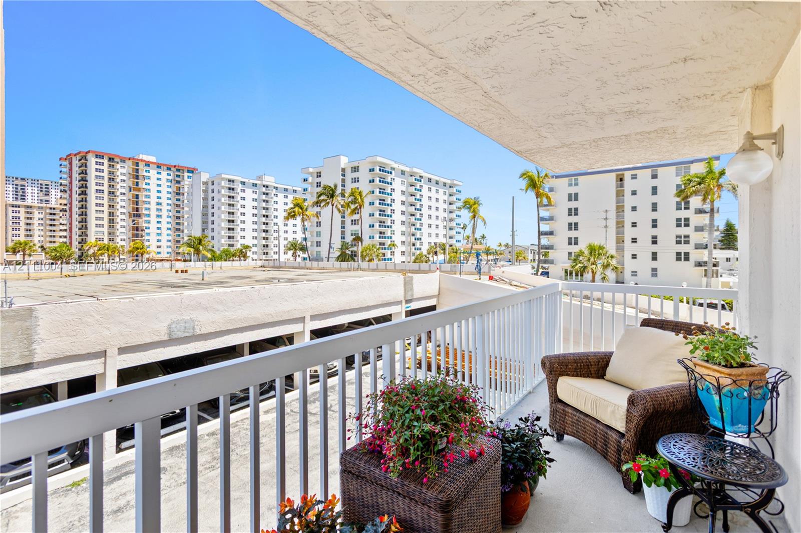 Covered balcony featuring concrete flooring, white metal railing, and attached wall-mounted lighting