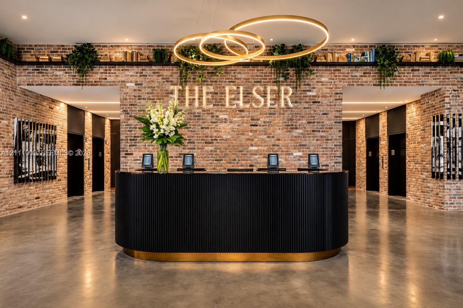 Lobby featuring exposed brick walls, a curved reception desk with fluted detailing and metallic base, polished concrete flooring, and an integrated tiered display shelf