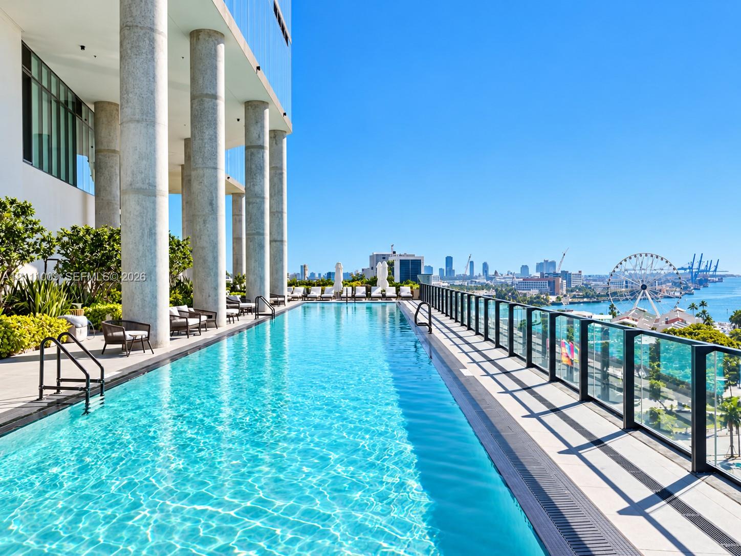 Elevated infinity-edge pool featuring structural concrete columns, glass pane railing, and composite decking