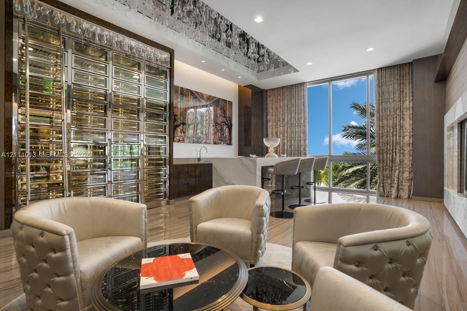 Custom climate-controlled wine display with glass and metal shelving, stone-topped built-in wet bar, recessed ceiling with crystal lighting detail, floor-to-ceiling windows, and polished stone-finish flooring