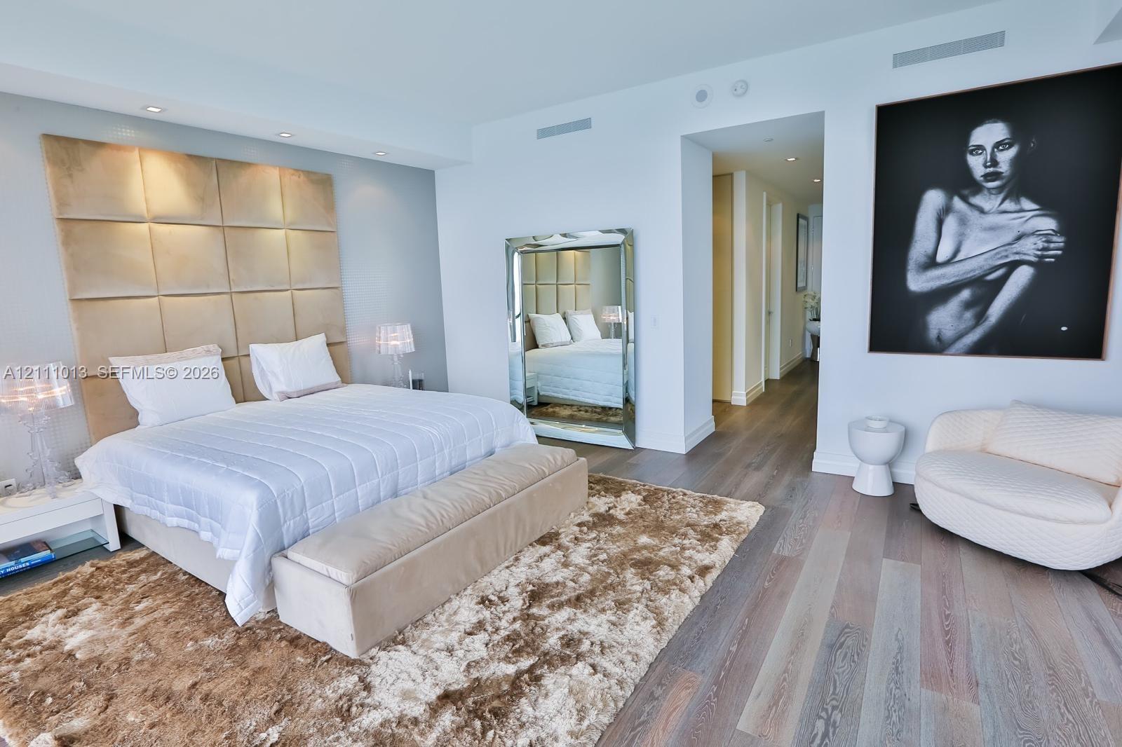 Expansive living space featuring wood-finish flooring, recessed ceiling lighting, and a floor-to-ceiling upholstered wall panel accent