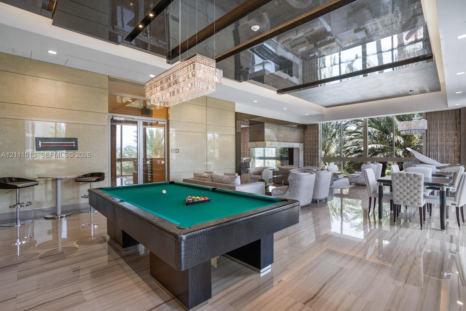 Expansive interior featuring high-gloss tile flooring, reflective tray ceilings, oversized floor-to-ceiling windows, and a multi-tiered crystal chandelier