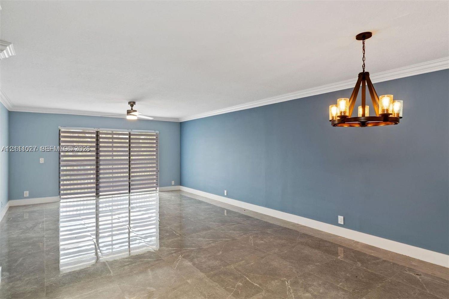 Polished tile flooring, crown molding, multi-light wagon wheel chandelier, ceiling fan, and sliding glass doors with roller shades Polished tile flooring, crown molding, multi-light wagon wheel chandelier, ceiling fan, and sliding glass doors with roller shades