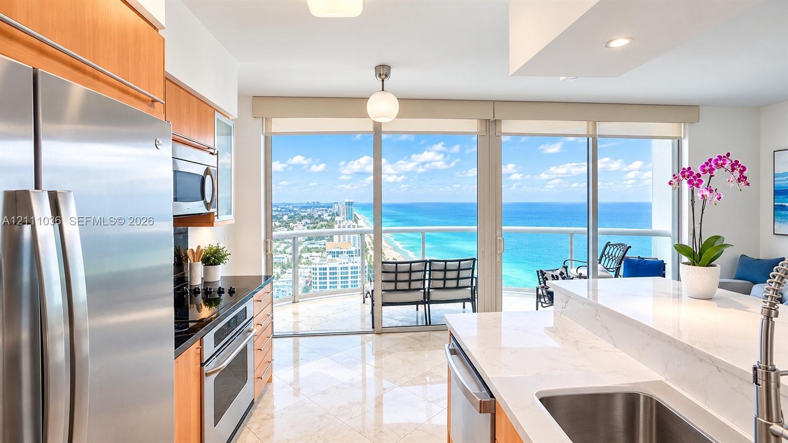 Kitchen featuring light-finish cabinetry, stone countertops, stainless steel appliances, polished tile flooring, and floor-to-ceiling glass doors opening to a balcony