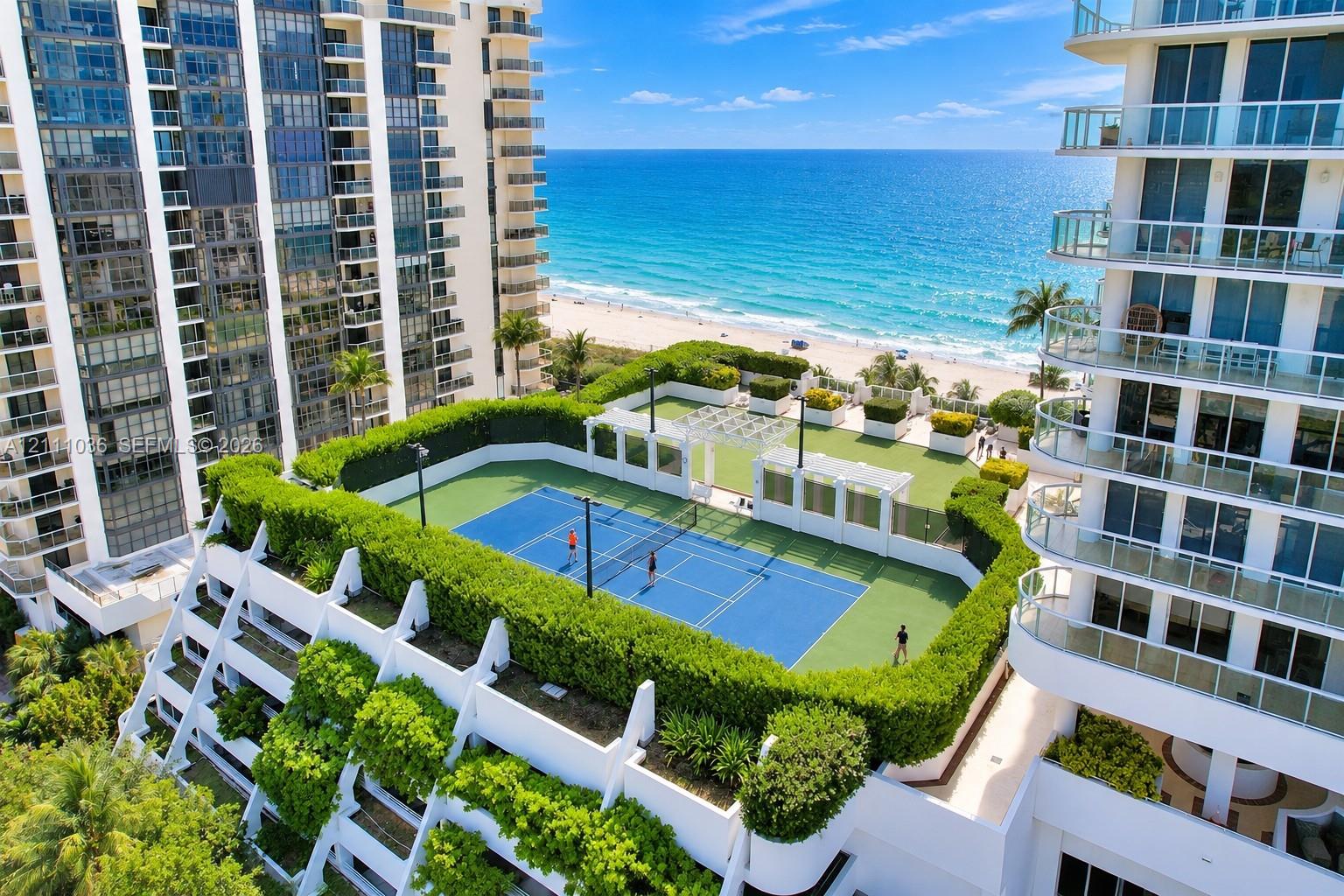 Rooftop recreational level featuring a tennis court, synthetic grass lawn area, perimeter hedge landscaping, and white pergola structures