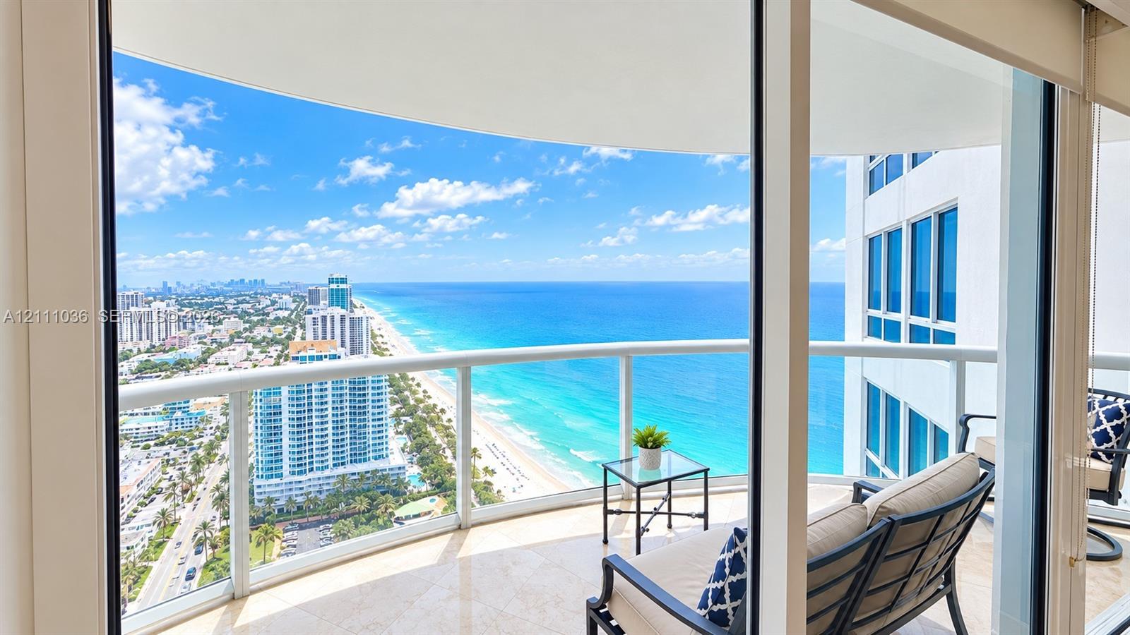 Covered wrap-around balcony featuring glass panel railings, stone flooring, and expansive coastal and urban scenery