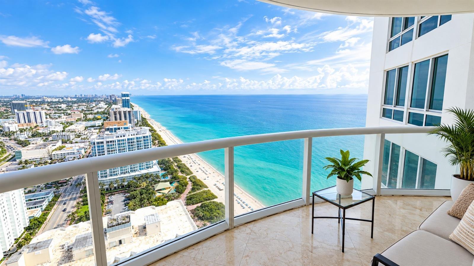 Private balcony featuring polished stone flooring and glass panel railings with an unobstructed coastal panorama