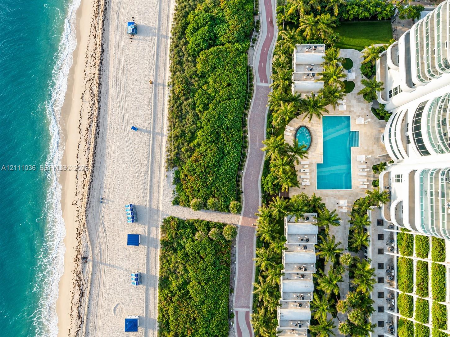 Oceanfront property featuring direct beach access, a rectangular swimming pool, a separate circular spa, paved pedestrian pathways, and lush tropical landscaping