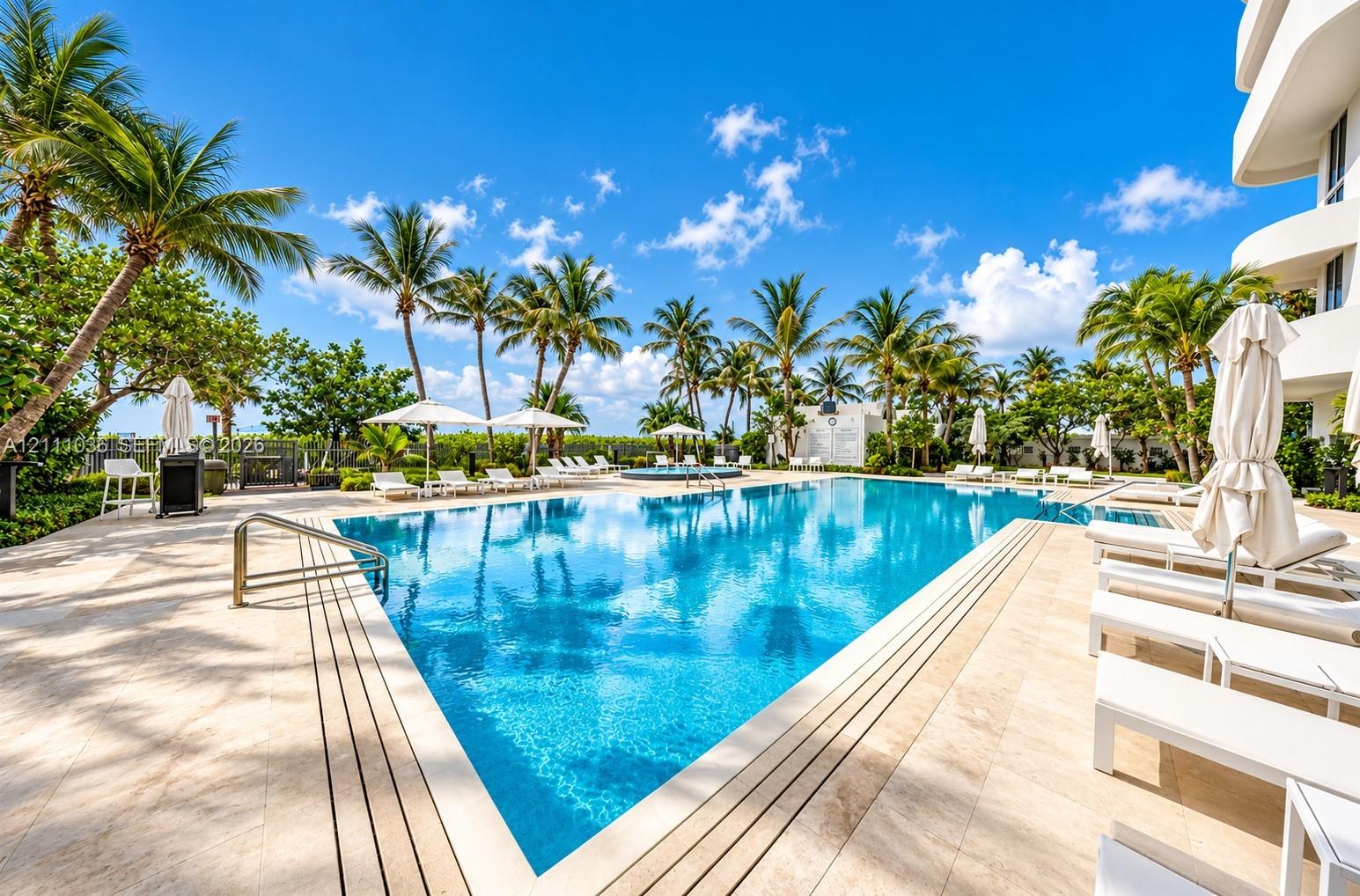 Swimming pool featuring stone decking, metal handrails, and mature palm trees