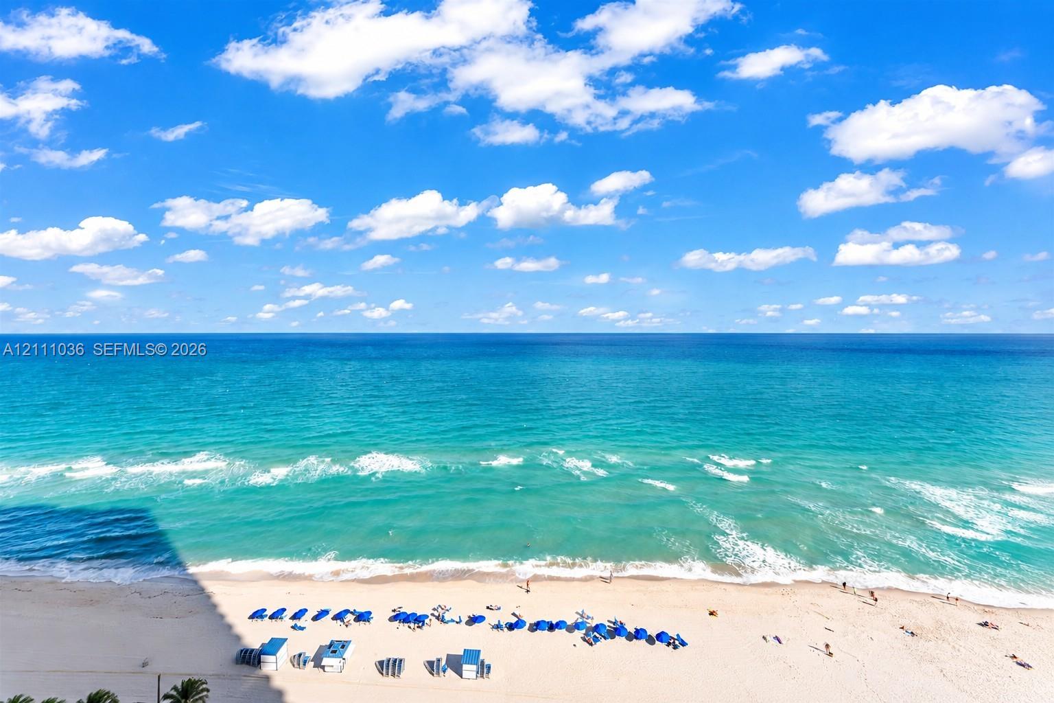 Elevated horizon with expansive ocean water, sandy shoreline, and clear skies