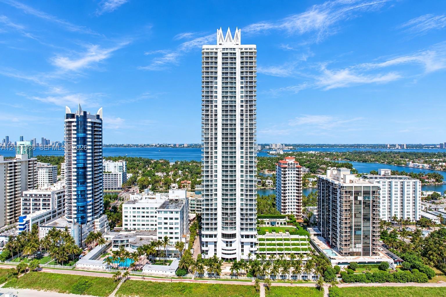 High-rise architectural exterior featuring a prominent crown design, multiple levels of private balconies, concrete construction, and extensive glass facade