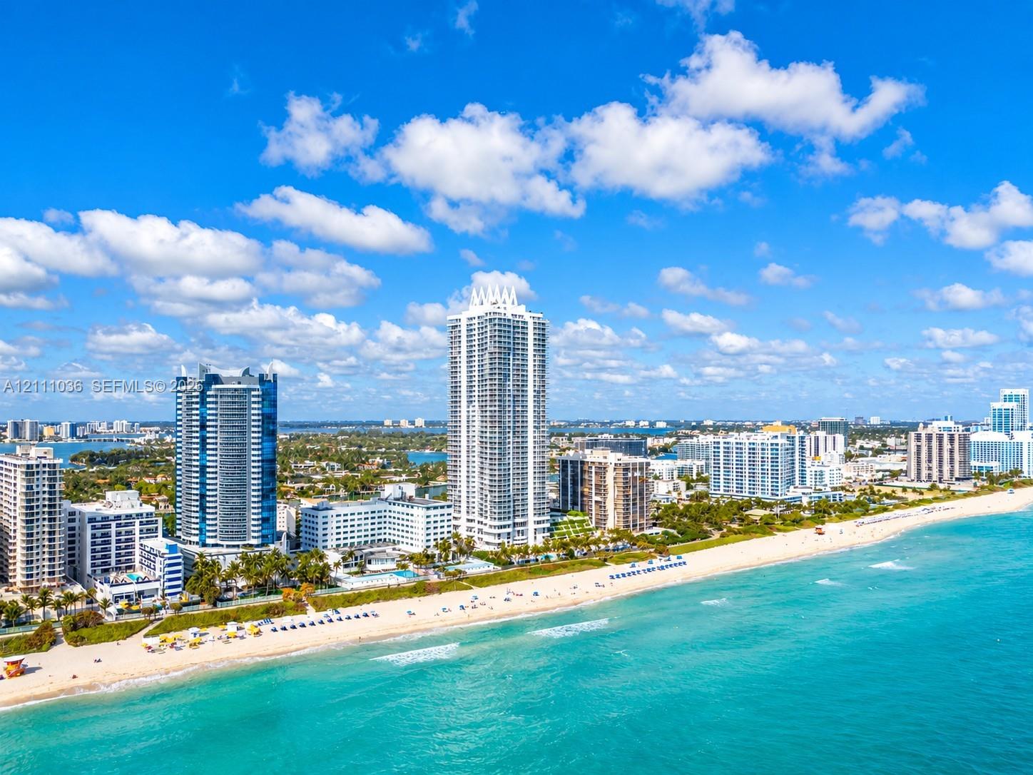 Aerial perspective of coastal high-rise towers positioned along a sandy shoreline with direct oceanfront exposure
