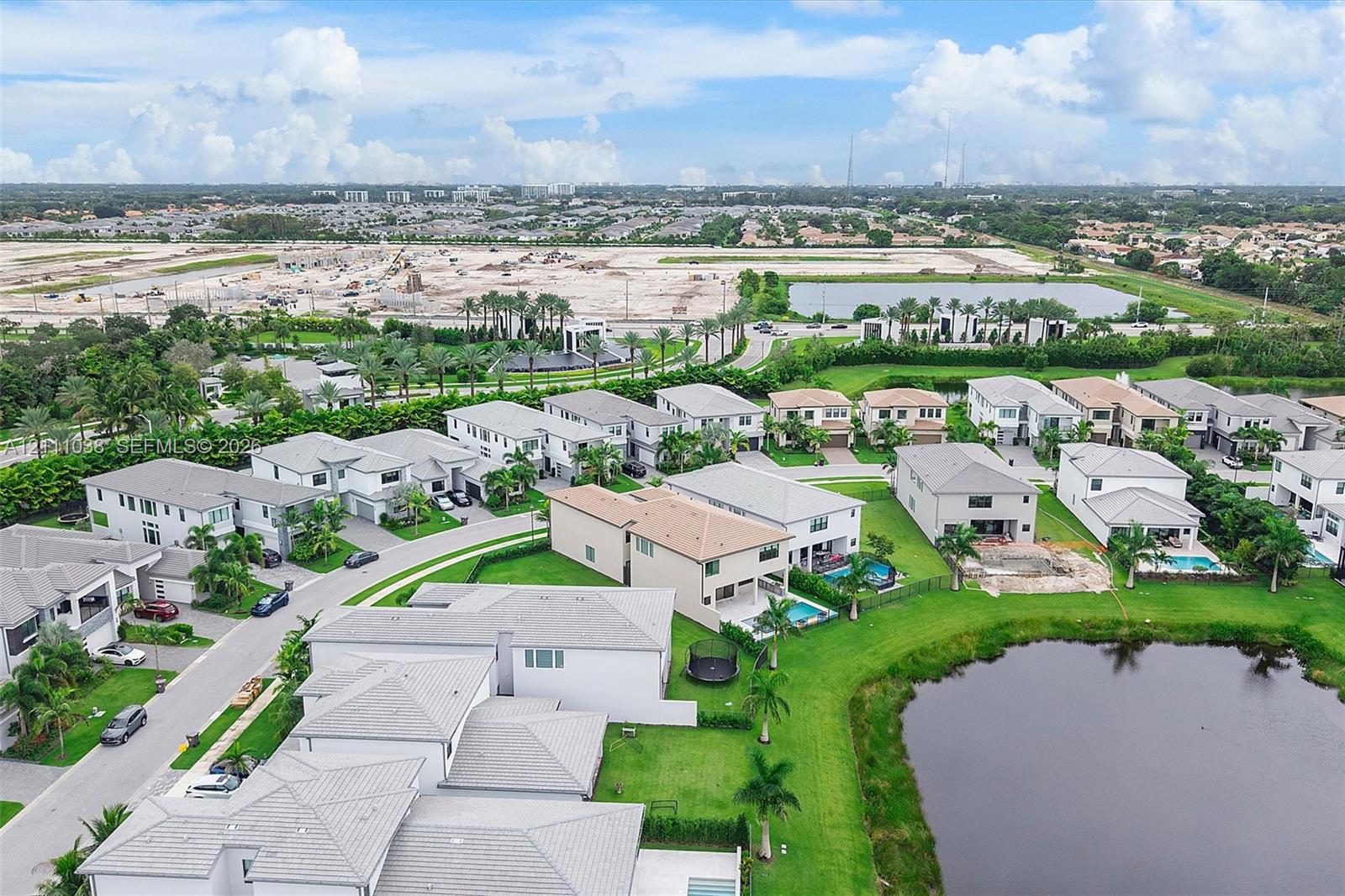Aerial perspective featuring multi-story residential structures with neutral-toned stucco exteriors and pitched roofs, situated on landscaped lots with private swimming pools and water frontage