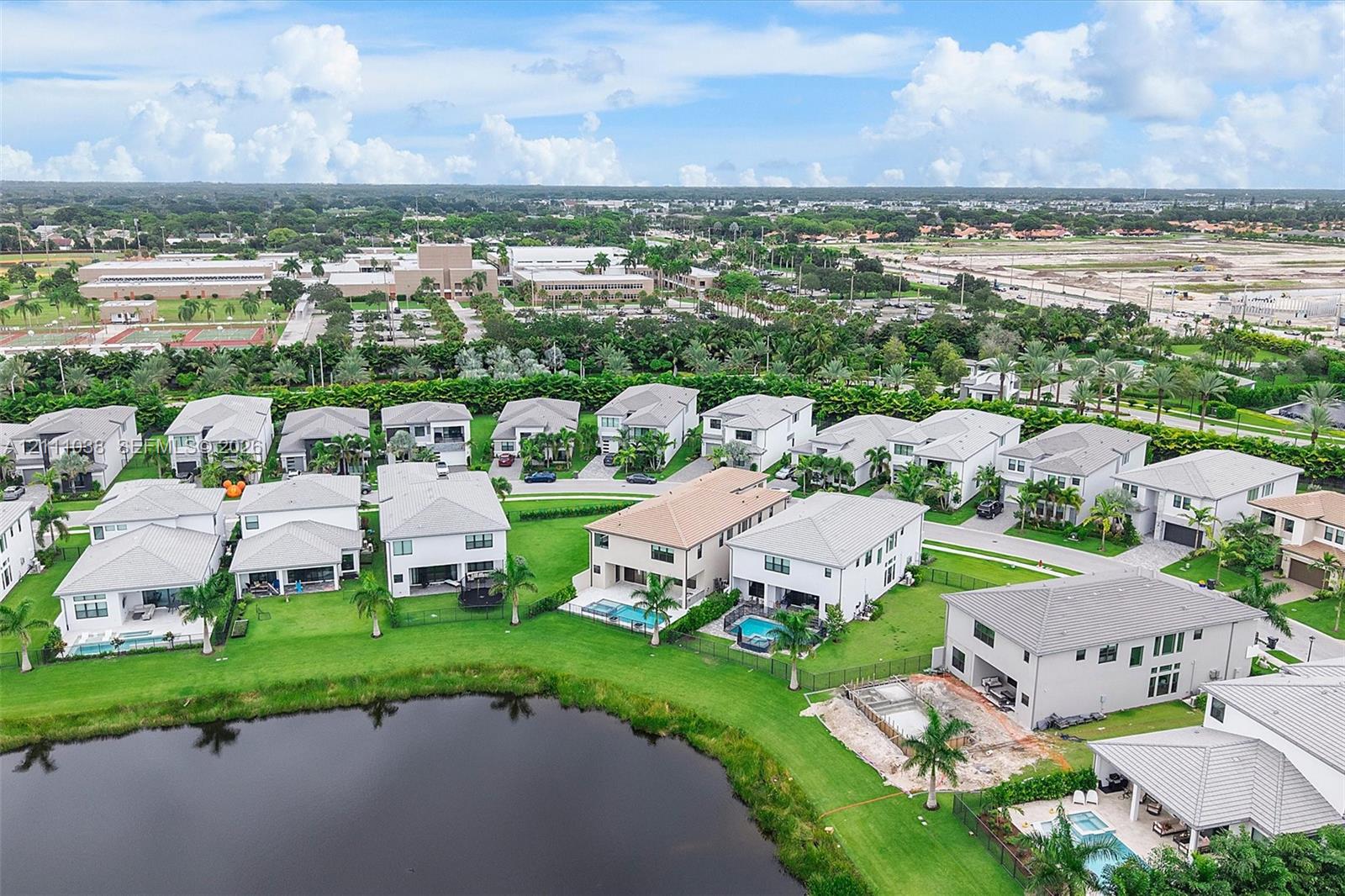 Aerial perspective of a residential community featuring waterfront lots, multi-story dwellings, tile roofing, and managed landscaping