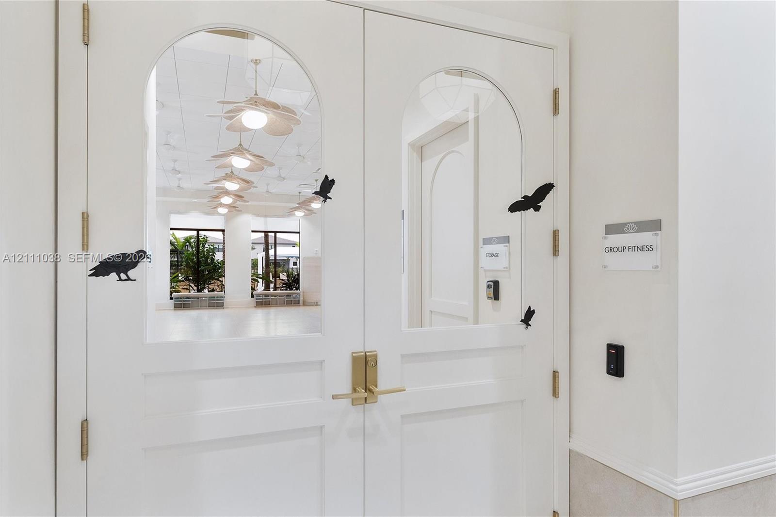Double doors featuring arched glass panels, brass-finish lever hardware, and electronic keycard access entry