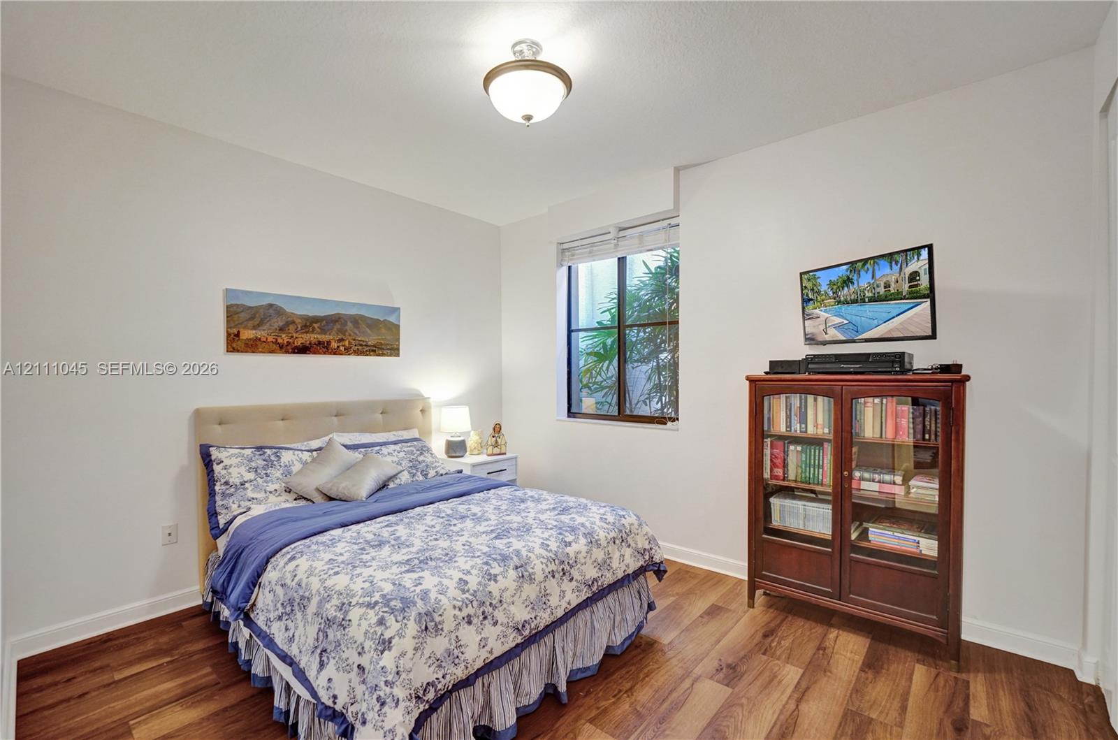 Room featuring wood-finish flooring, neutral walls, a single-pane window, and a central ceiling-mounted light fixture