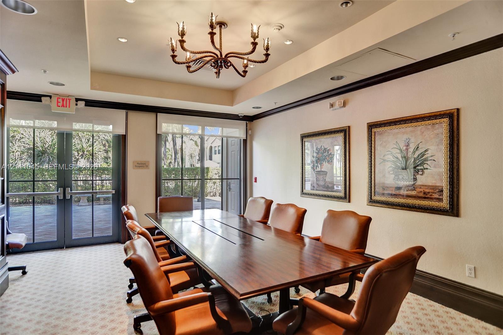 Conference room featuring a tray ceiling, decorative metal chandelier, crown molding, and floor-to-ceiling glass-paned doors