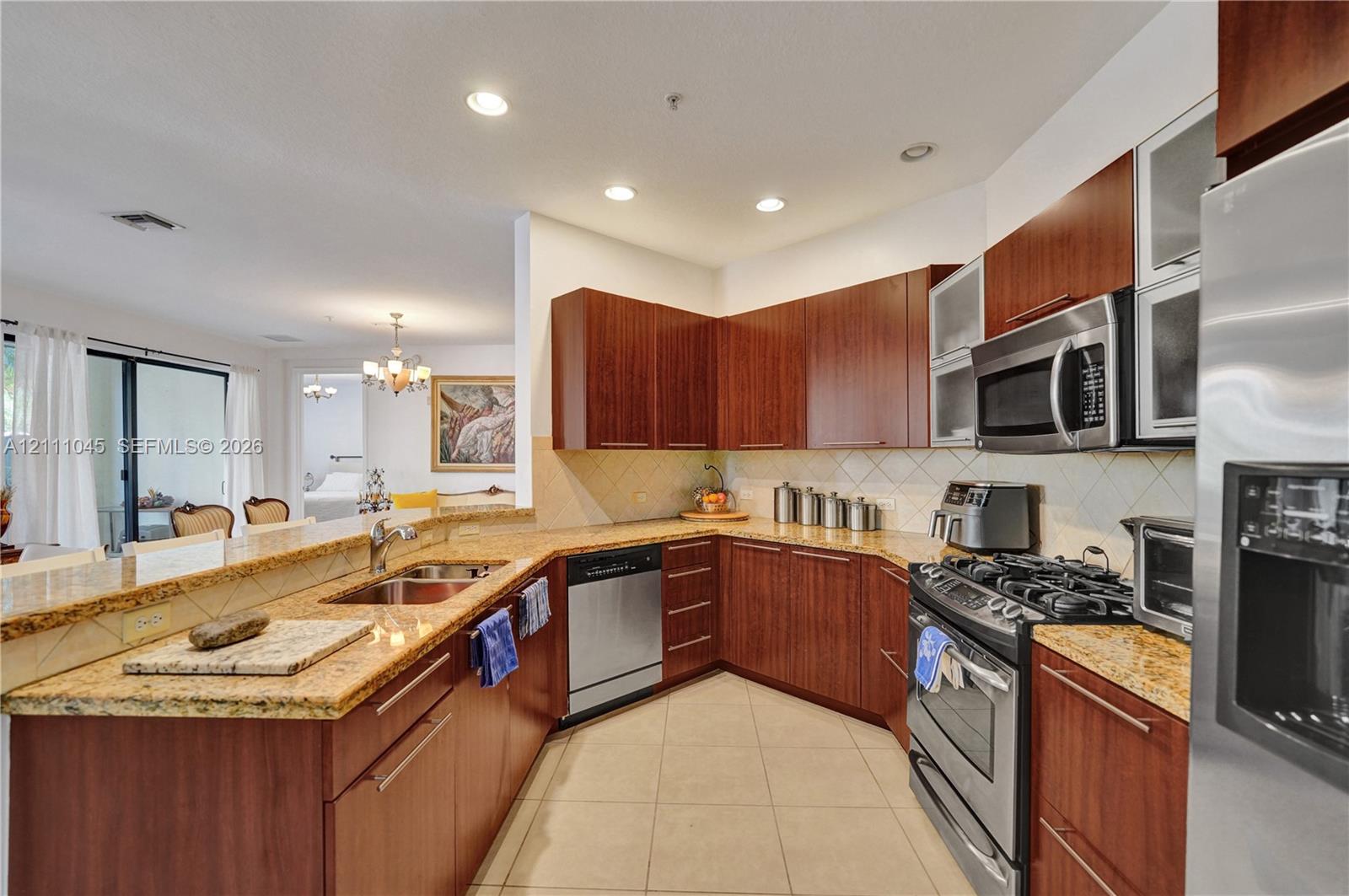 Kitchen featuring flat-panel wood cabinetry, stone countertops, tiled backsplash, stainless steel appliances, and recessed lighting