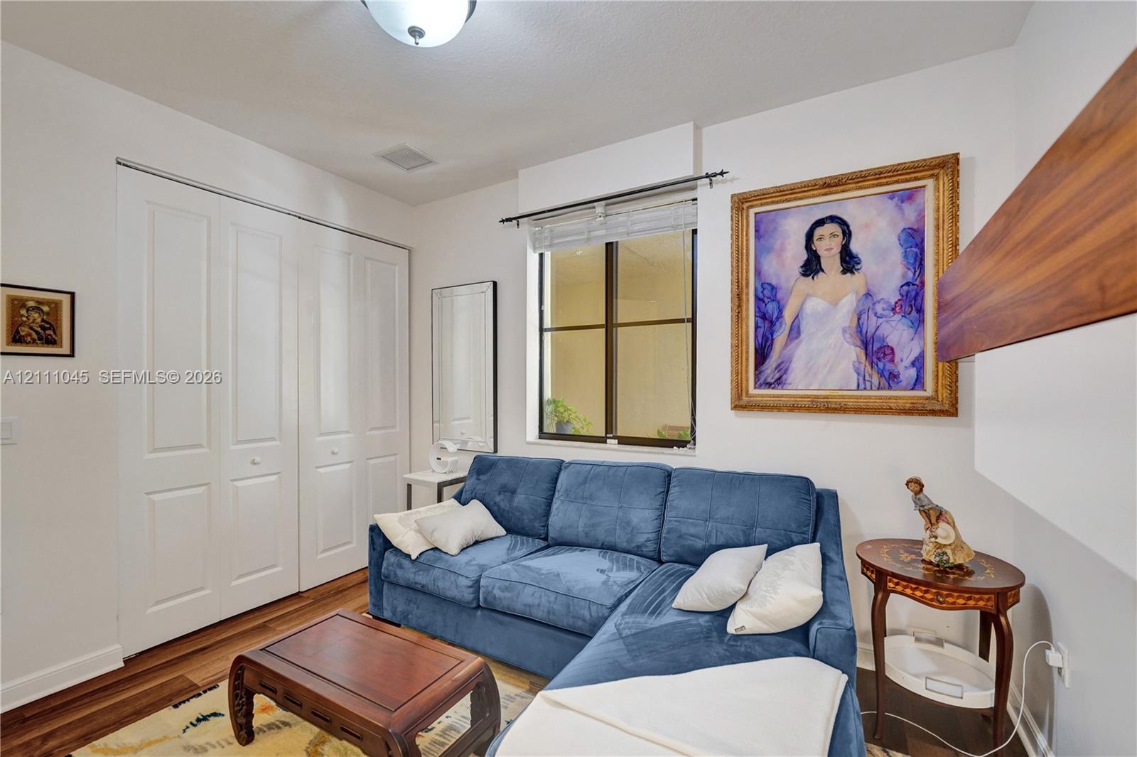 Room featuring wood-finish flooring, dual-panel closet doors, a single-hung window with a metal frame, and a flush-mount ceiling light fixture