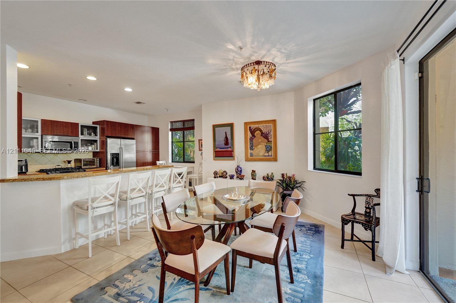 Kitchen featuring a stone-surface breakfast bar, dark-finish cabinetry, recessed lighting, tile flooring, and a decorative flush-mount fixture