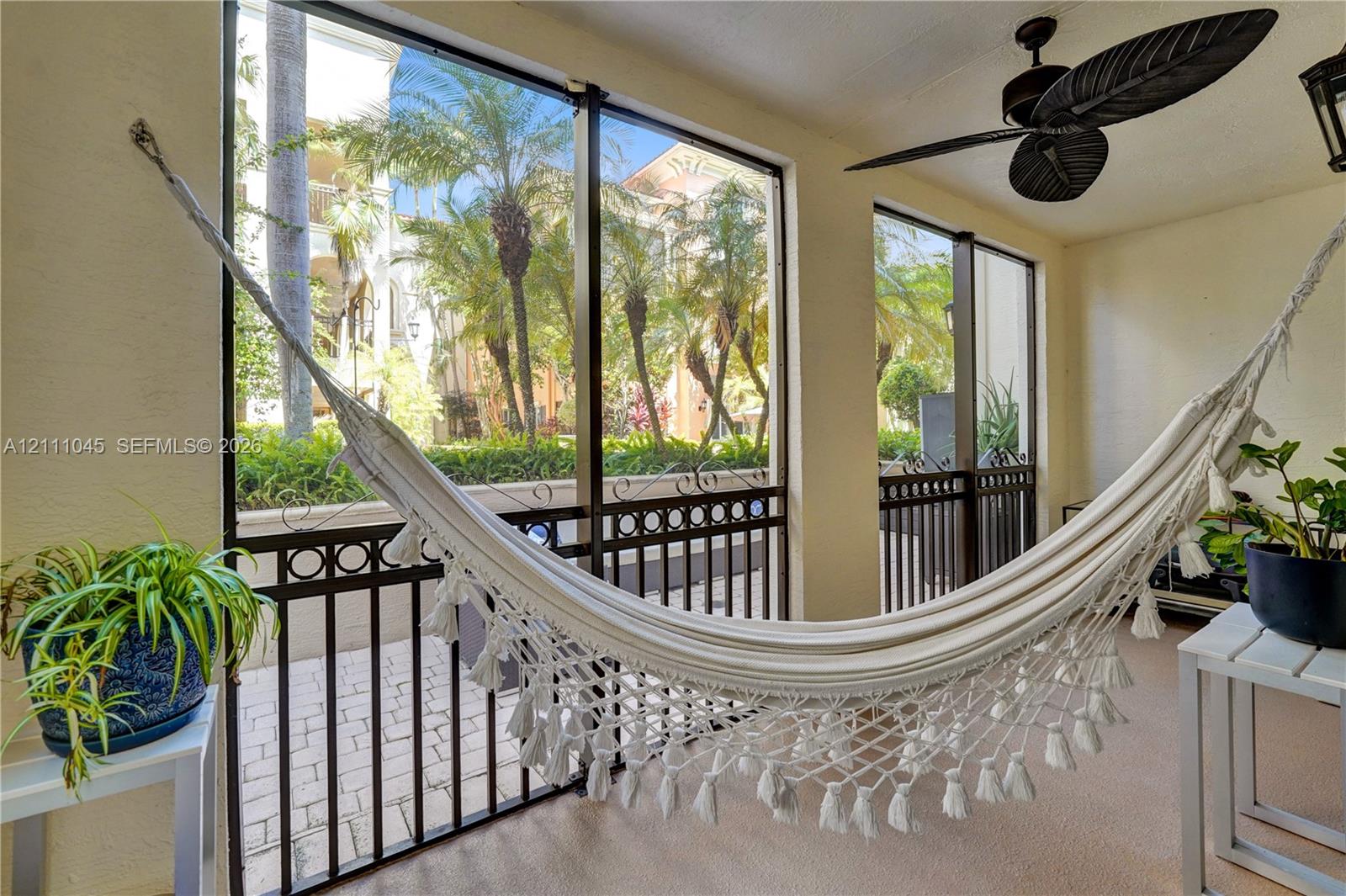Screened-in porch featuring full-height window panels, black metal decorative railings, and a ceiling-mounted fan