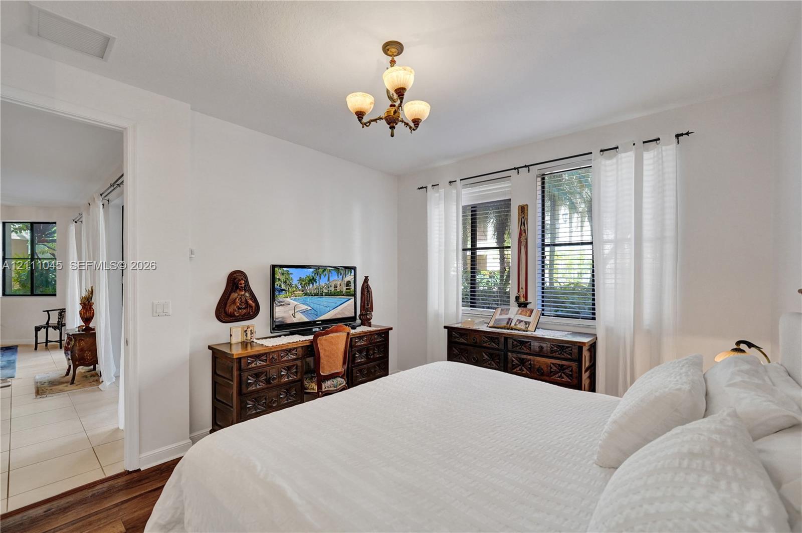 Interior space featuring three-light chandelier, dual windows with horizontal blinds, and wood-finish flooring