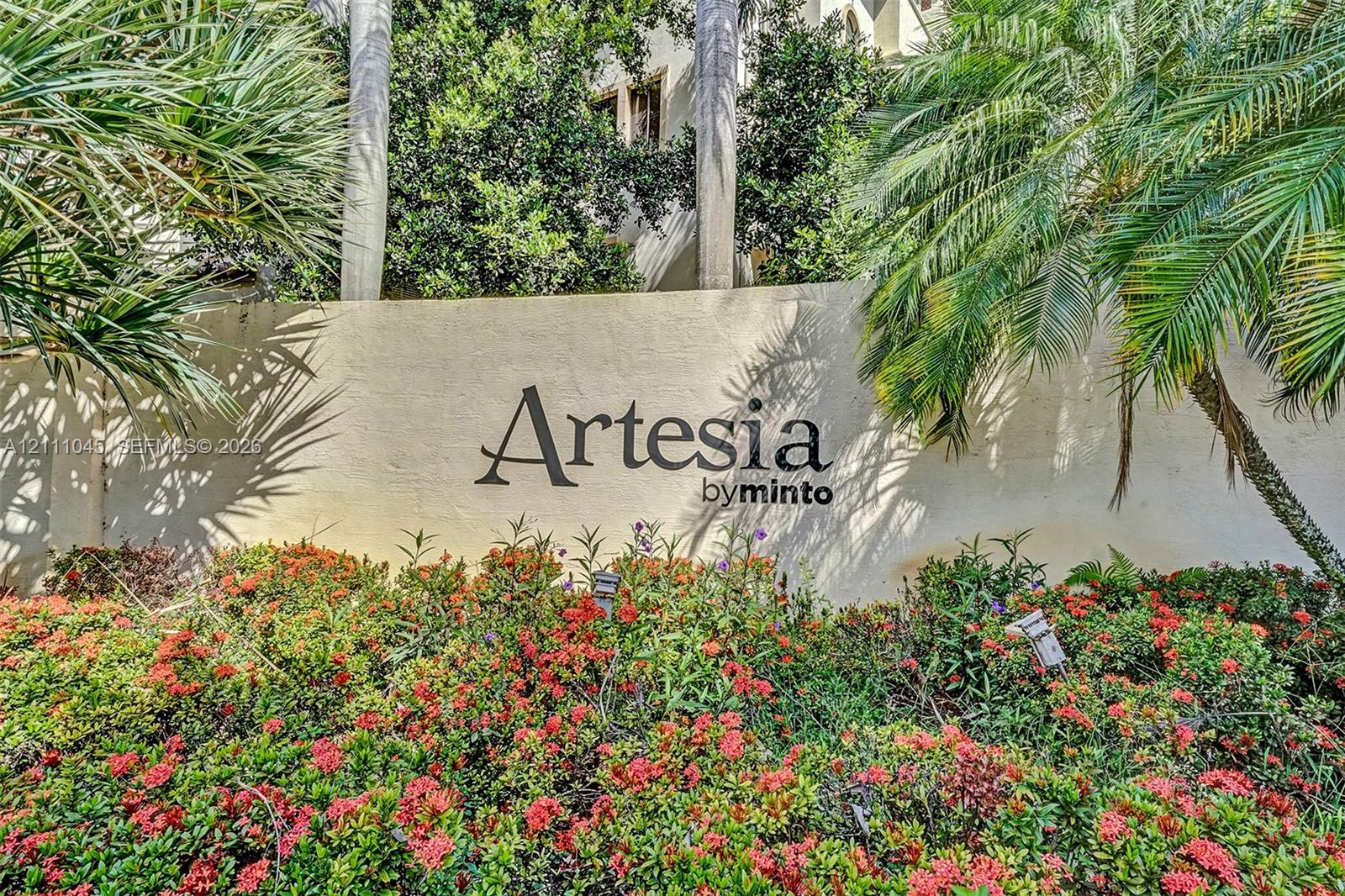 Community monument signage featuring dimensional lettering set against a smooth stucco wall, surrounded by mature palm trees and established flowering shrubbery Community monument signage featuring dimensional lettering set against a smooth stucco wall, surrounded by mature palm trees and established flowering shrubbery