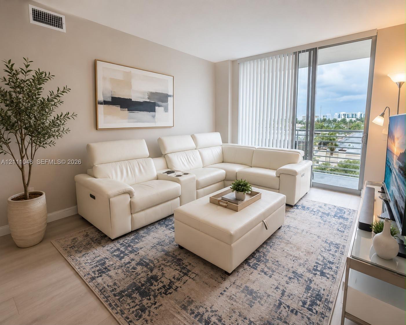 Living area featuring neutral wall paint, wood-finish flooring, and a glass sliding door providing exterior access Living area featuring neutral wall paint, wood-finish flooring, and a glass sliding door providing exterior access