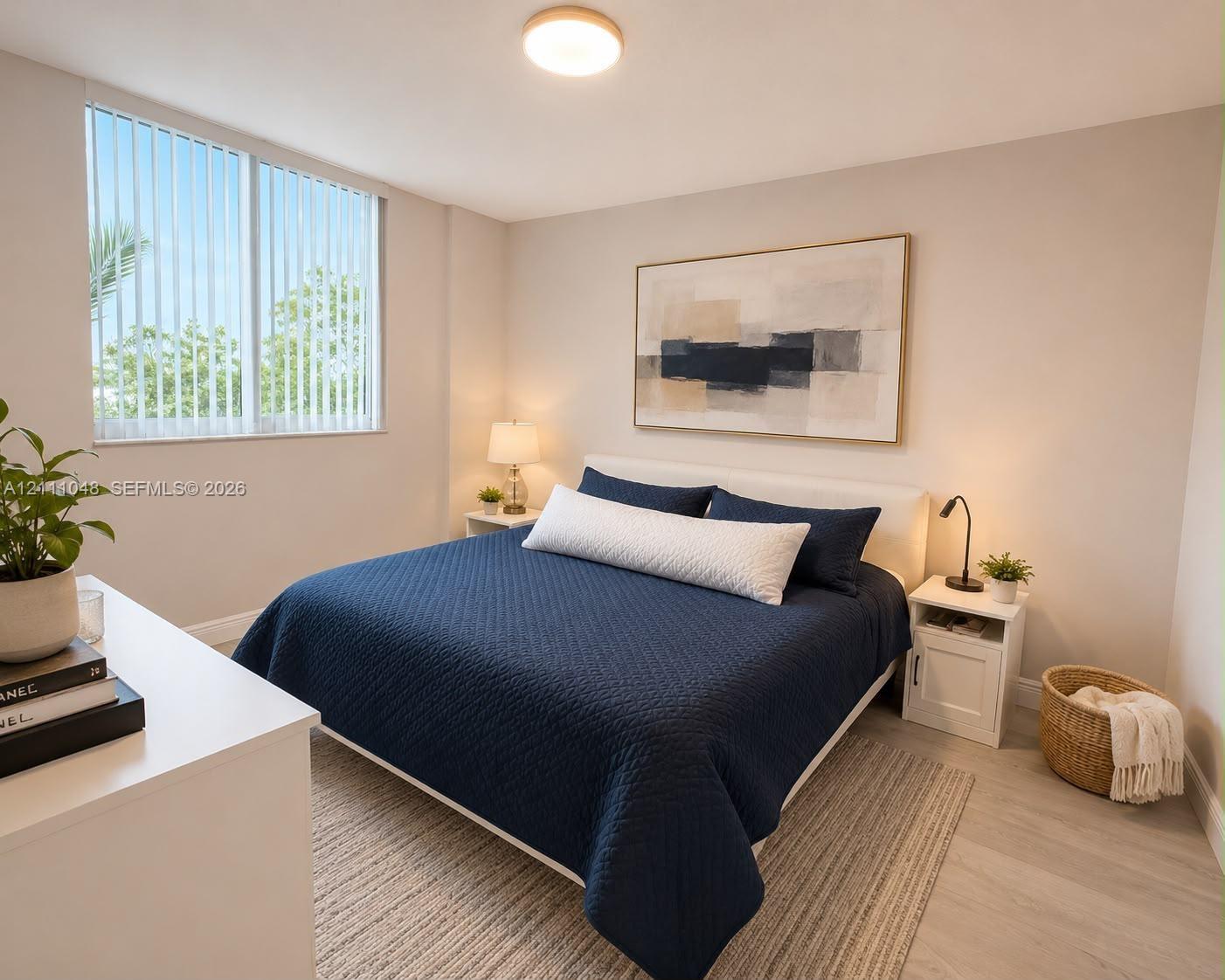 Neutral wall tones, wood-finish flooring, and a large window featuring vertical blinds Neutral wall tones, wood-finish flooring, and a large window featuring vertical blinds