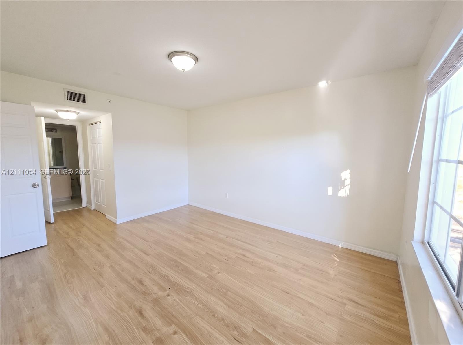 Room featuring wood-finish flooring, multi-pane windows, flush-mount ceiling lighting, and panel doors