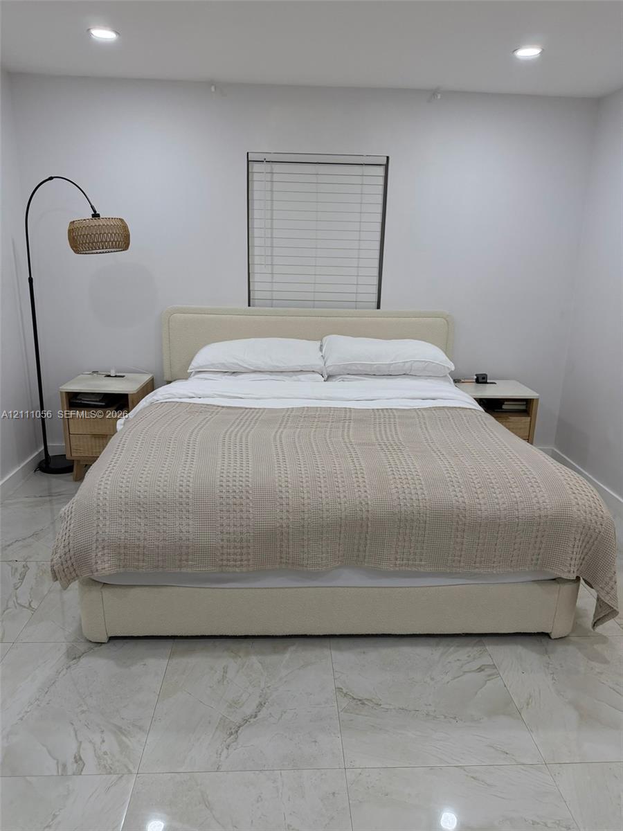Large-format tile flooring, recessed ceiling lighting, and horizontal window blinds