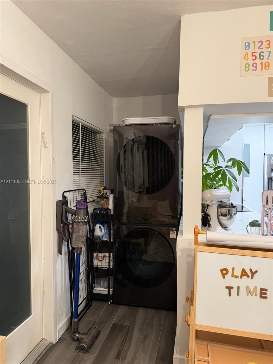 Open-concept interior featuring wood-finish flooring, a pass-through window with a serving ledge, an exterior door with a glass inlay, and contemporary multi-bulb ceiling lighting