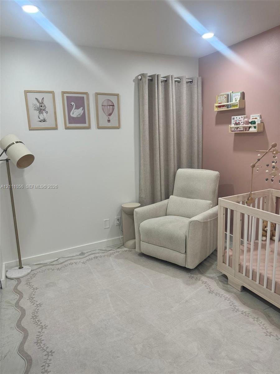 Room featuring recessed lighting, a neutral wall-to-wall carpet, and a custom accent wall with wall-mounted floating wood shelving