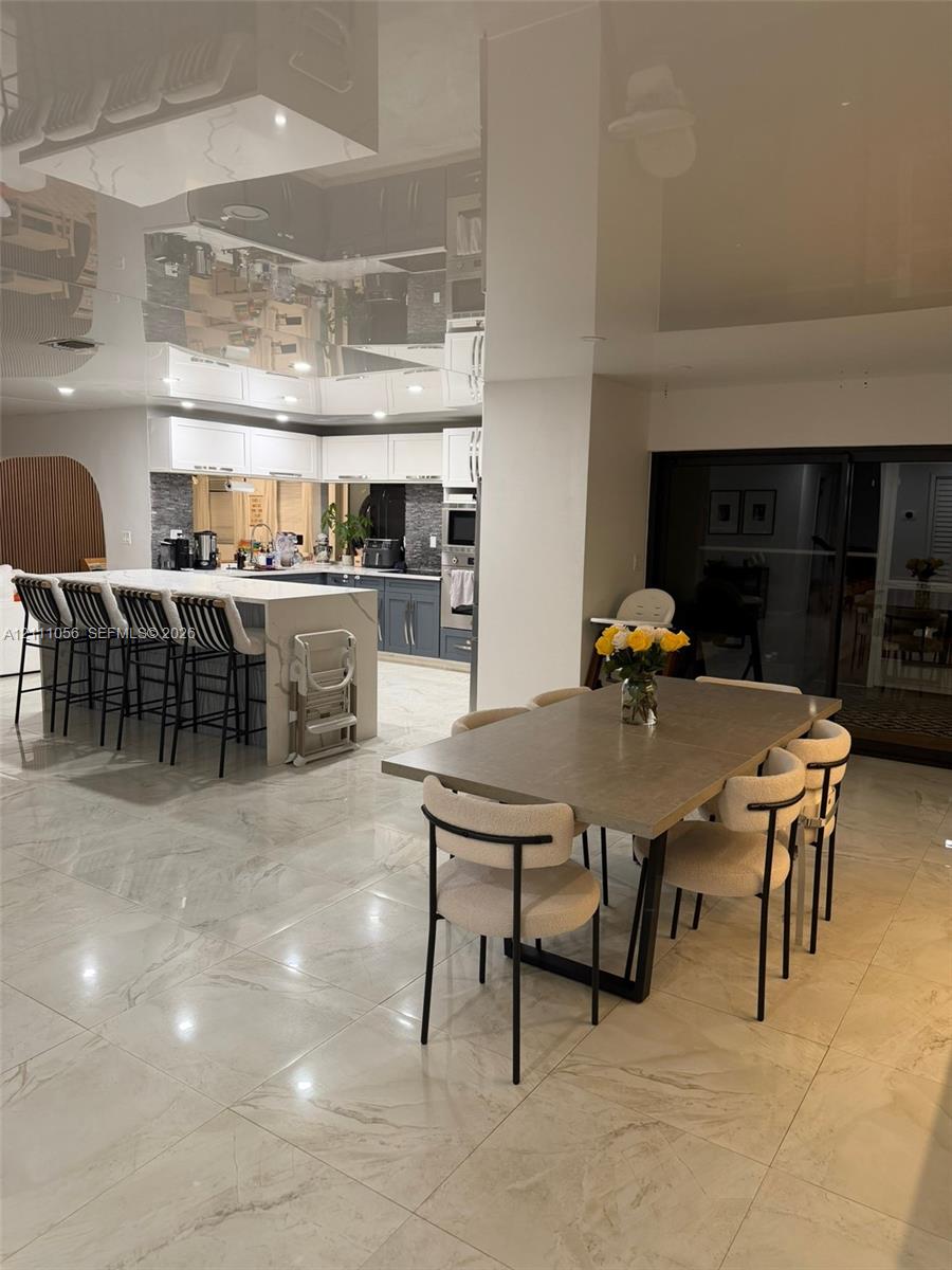 High-gloss reflective ceiling, large-format polished stone-finish floor tiling, recessed lighting, and integrated island cabinetry