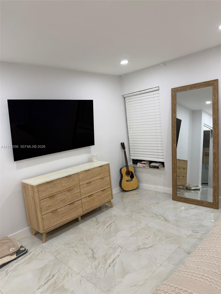 Large-format tile flooring, recessed ceiling lighting, and a horizontal window with slatted blinds