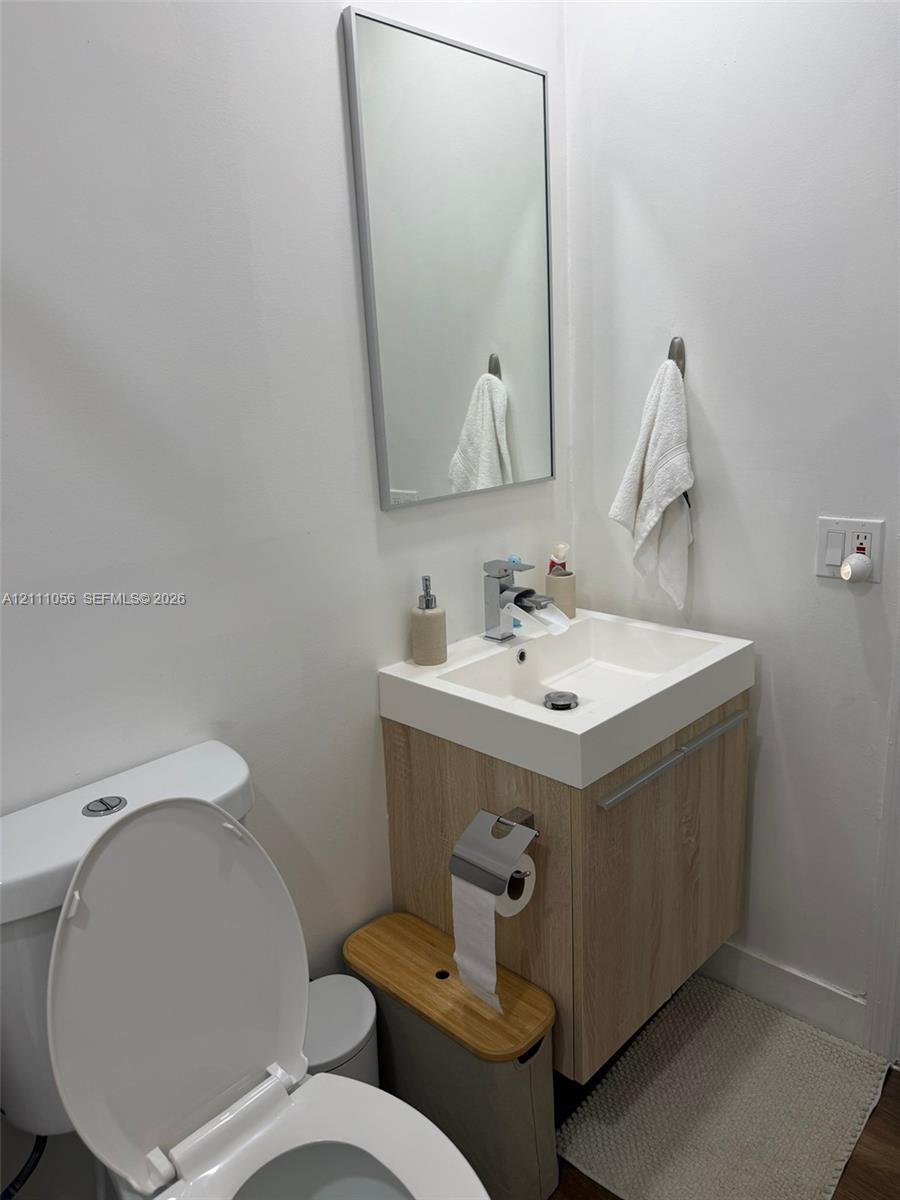 Architectural arched pass-through featuring a wall-mounted floating wood media console, linear wood-slat accent wall, tile flooring, and multi-arm geometric light fixture