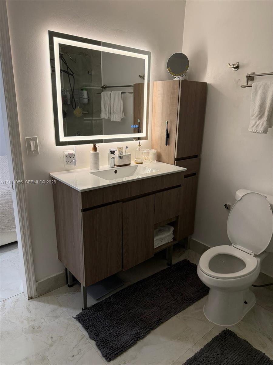 Large-format, stone-finish floor tiling with neutral veining, paired with white interior doors featuring classic panel detailing and polished metal hardware