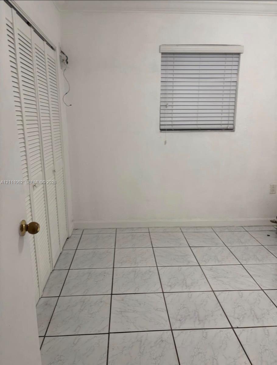 Tile flooring, bi-fold louvered closet doors, and window with fitted blinds