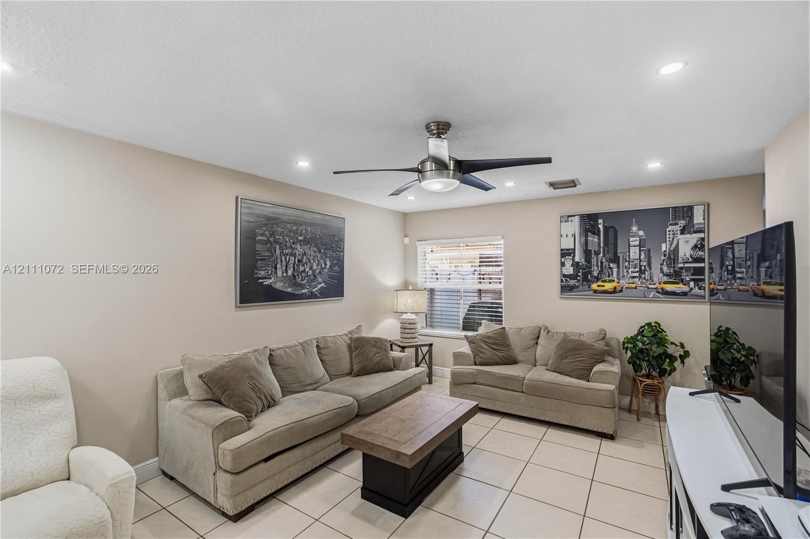 Neutral-toned interior space featuring large-format tile flooring, recessed lighting, and a modern metal ceiling fan