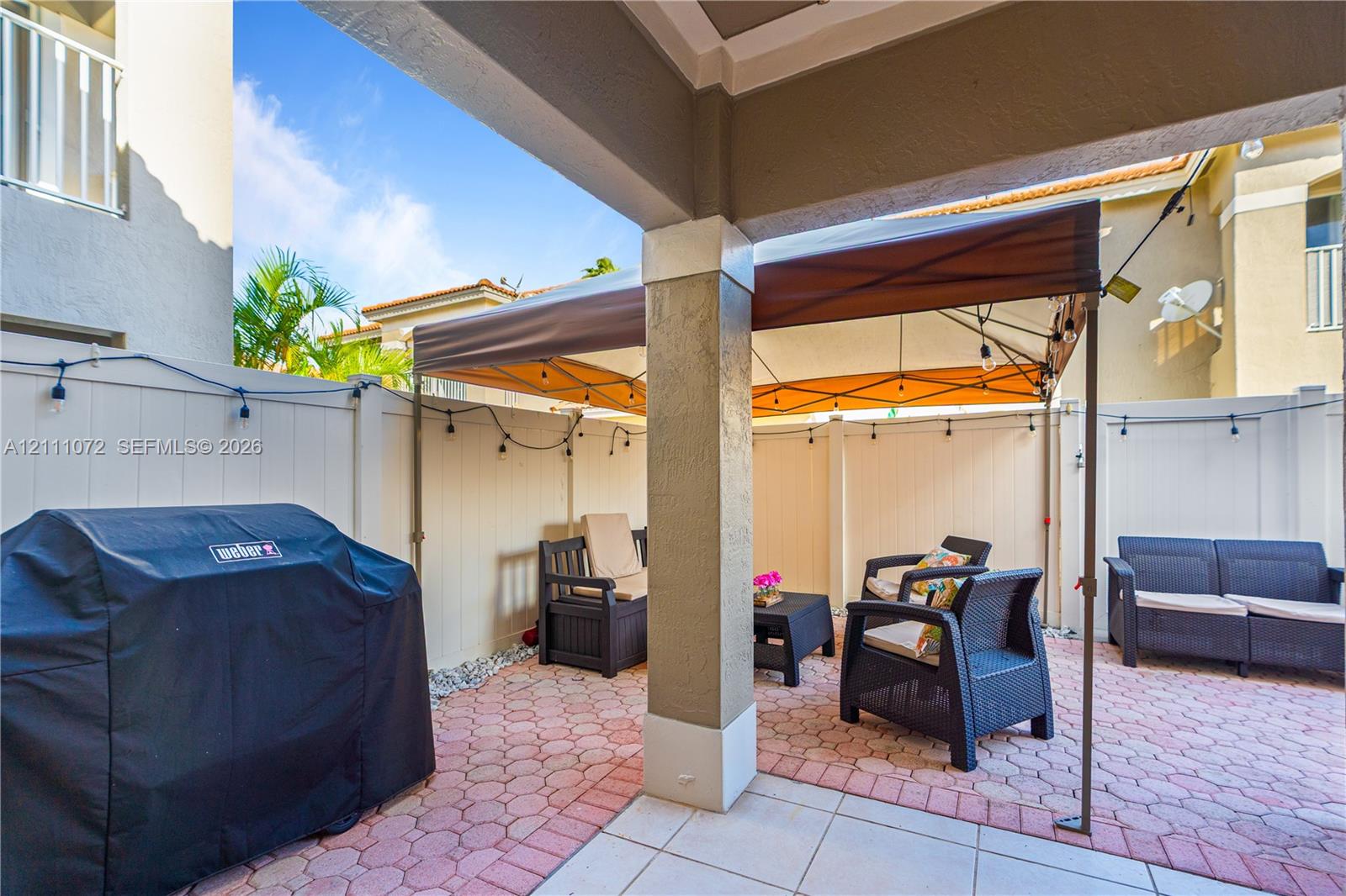 Covered patio featuring paver flooring, structural pillar, and vinyl privacy fencing