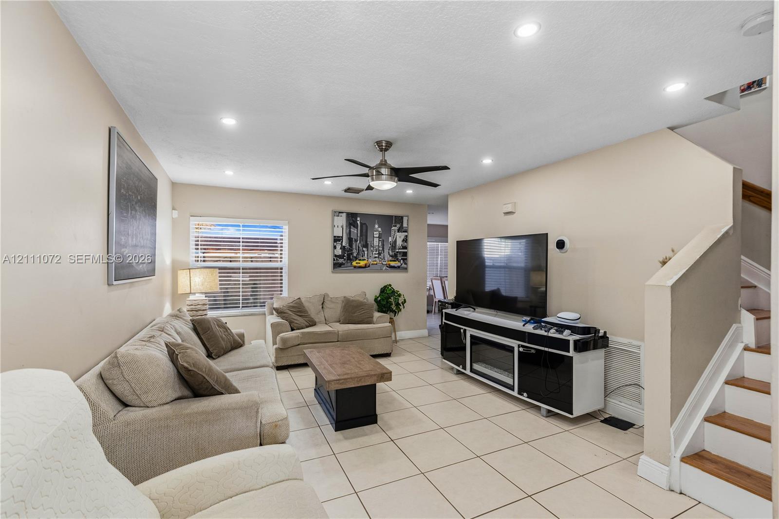 Large-format floor tile, recessed ceiling lighting, ceiling fan, and wooden stair treads