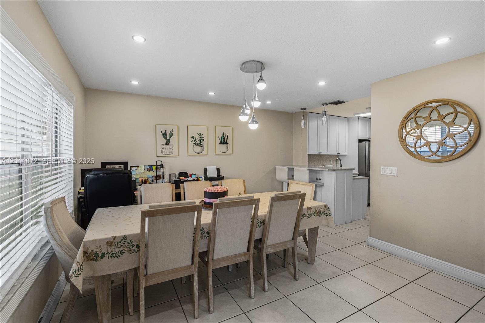 Open-concept floor plan featuring tile flooring, recessed lighting, a modern multi-pendant light fixture, and a kitchen peninsula with bar seating