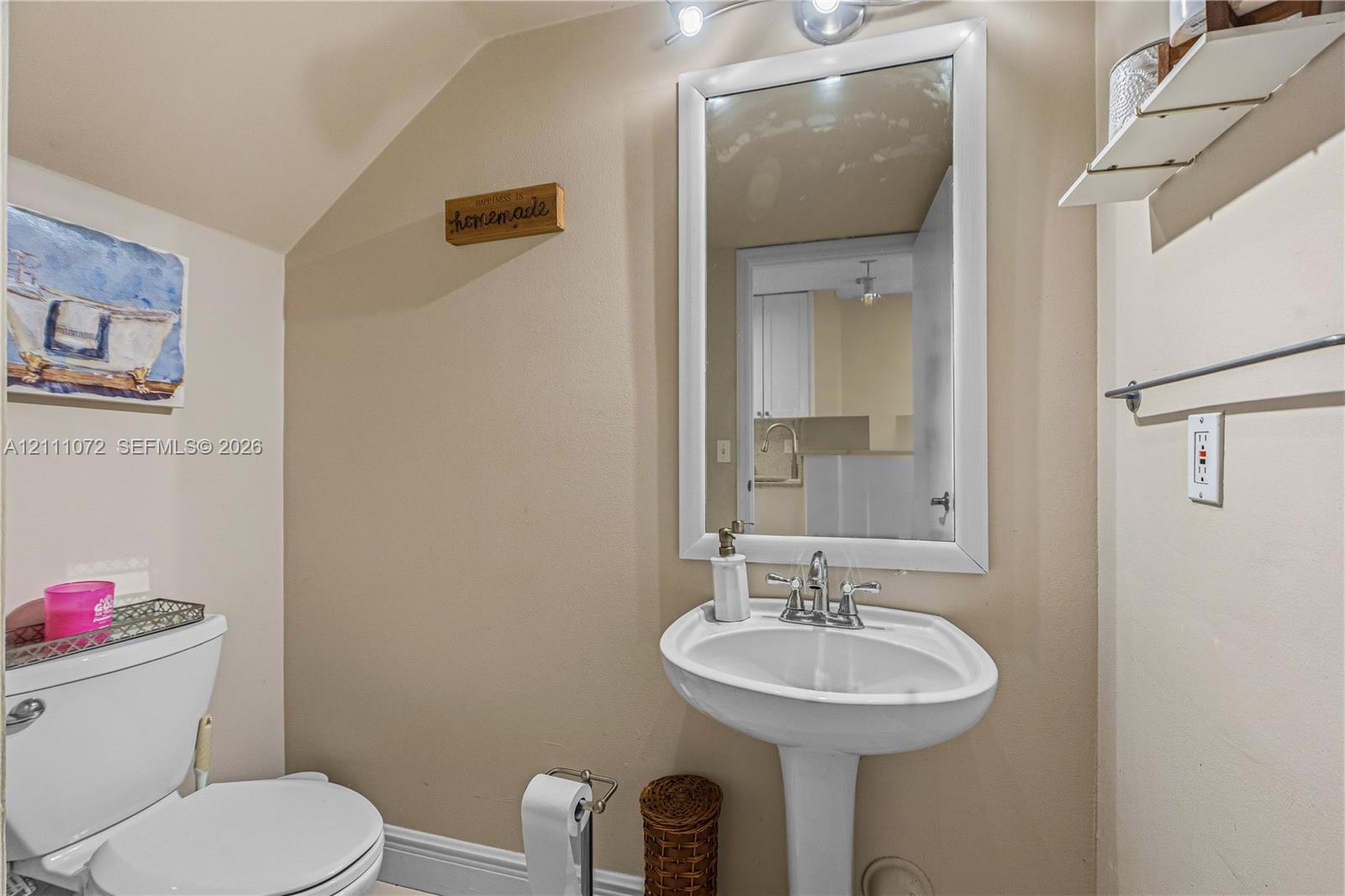 Powder room featuring a white pedestal sink, chrome faucet, framed wall mirror, and modern overhead vanity lighting